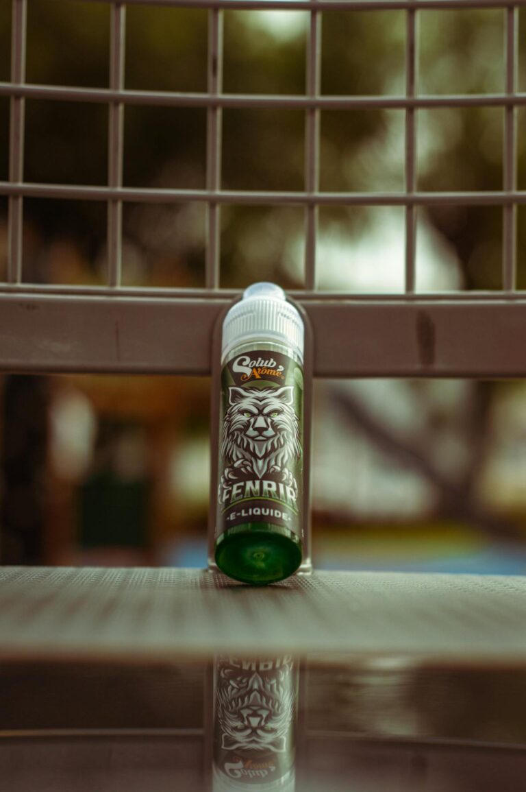A green e-liquid bottle on a bench outdoors in Casablanca, showcasing its design and packaging.